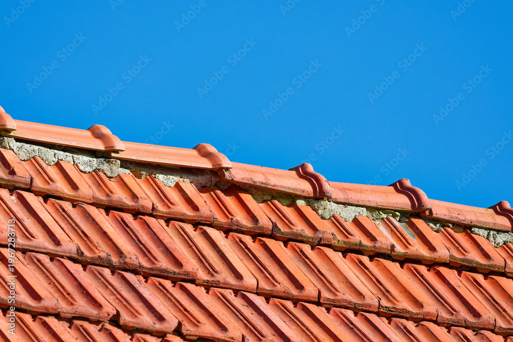 Naklejka premium Red clay roof tiles under clear blue sky on a sunny day
