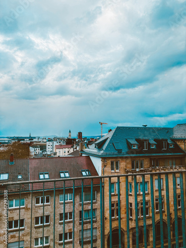 Moody European Cityscape with Historic Rooftops, Church Towers  under Dramatic Cloudy Sky