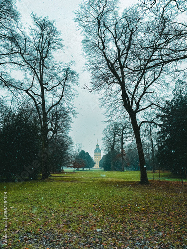 Snowfall Serenity in a Historic European Park with a Baroque Palace Tower Framed by Bare Winter Trees