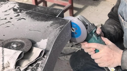 Worker uses tool to shape stone block in workshop during daytime hours