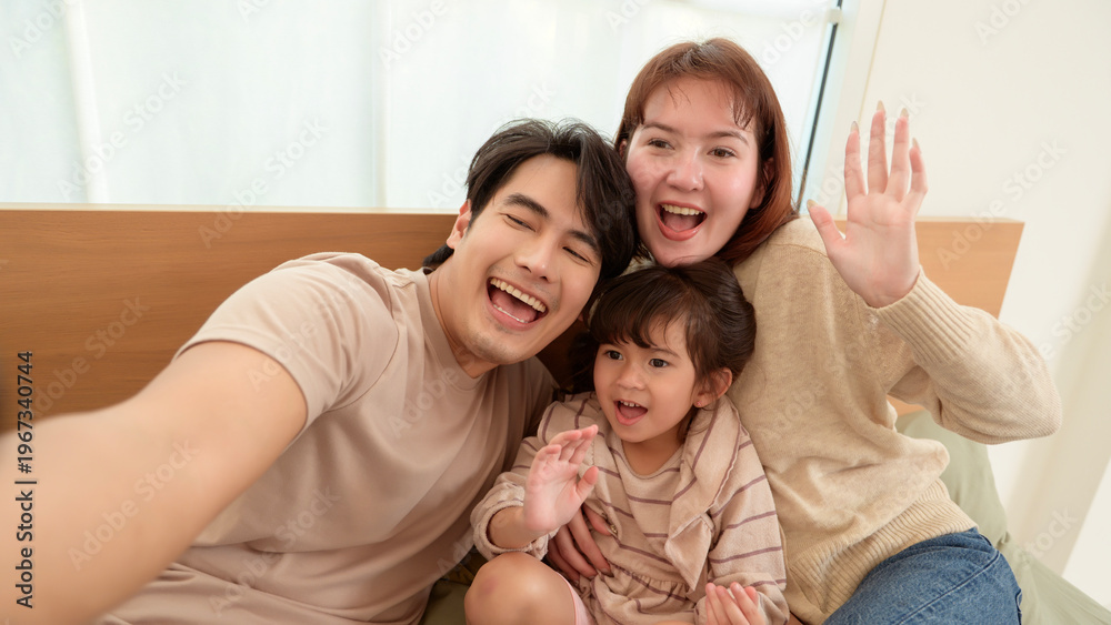 Fototapeta premium Family Takes a Selfie at Home With Smiles and Waves During a Fun Moment Together