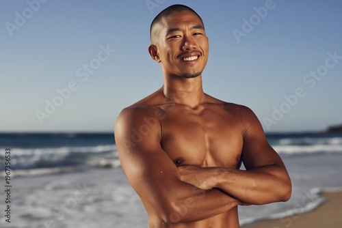 Shirtless man standing with arms crossed on beach shore