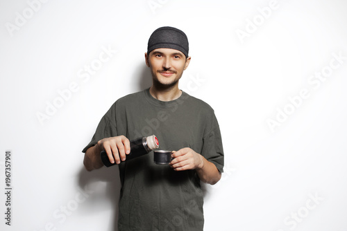Young man with thermos and mug in hands isolated on white background.