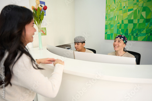 Patient interacting with clinic reception staff at front desk