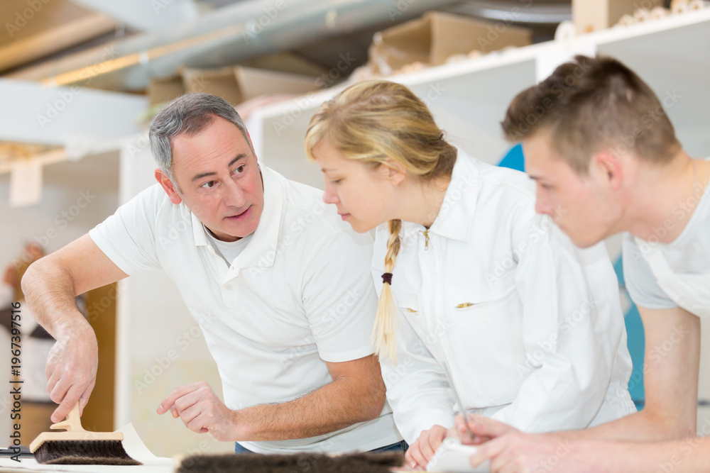 Obraz premium supervisor showing apprentices how to use wallpaper brush