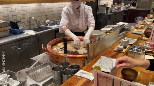 Osaka, Japan - March 27, 2026: Chef Frying Tempura in Traditional Copper Pot at Japanese Restaurant Counter