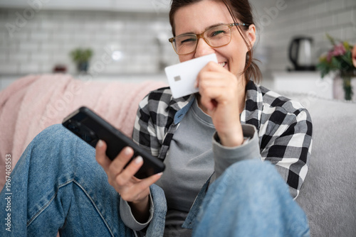 Young Woman Shopping Online With A Smartphone While Laughing And Holding A Paying Card