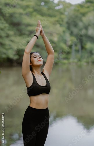 Asian woman practicing yoga on nature. Girl meditating outdoors. Female with slim, strength and flexibility body. Healthy lifestyle.