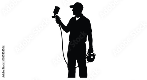 Painter using spray gun defined against a bright background silhouette
