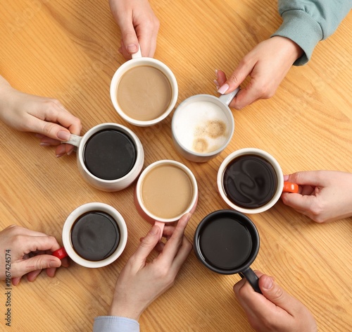 Friends with cups of aromatic coffee at wooden table, top view