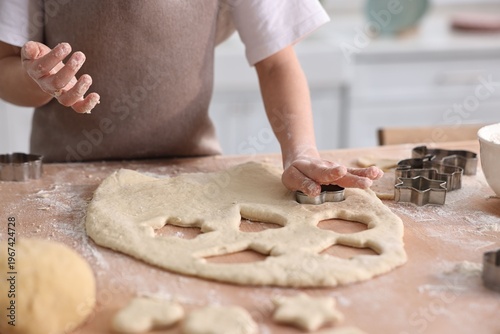 Tableau sur toile Child cutting cookies at table indoors, closeup