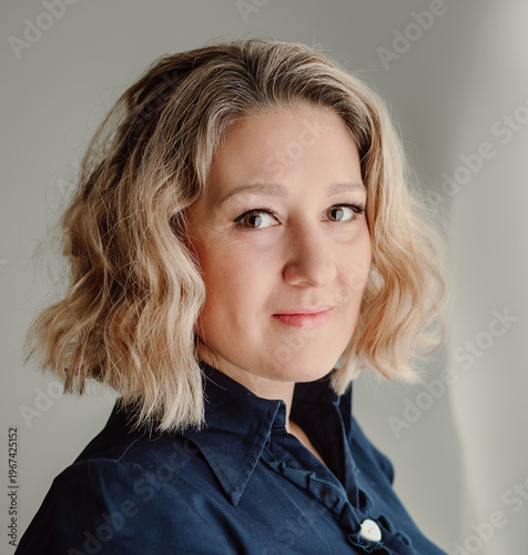 Woman portrait with soft smile looking at camera in natural light
