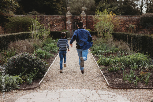 Father and son running together along garden path outdoors