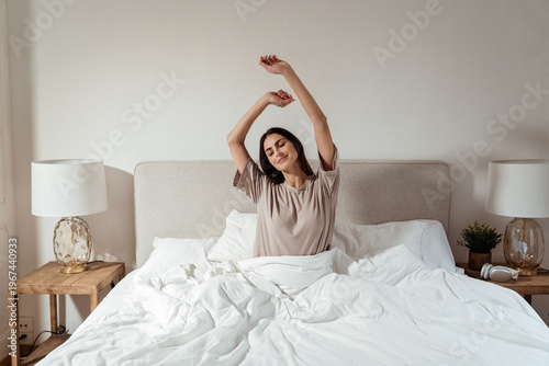 Happy woman stretching in bed after waking up, morning routine and healthy lifestyle