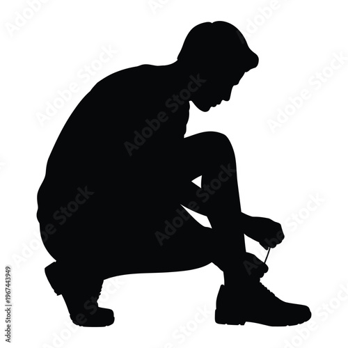 A man is crouching down tying his shoelaces in a stark black silhouette