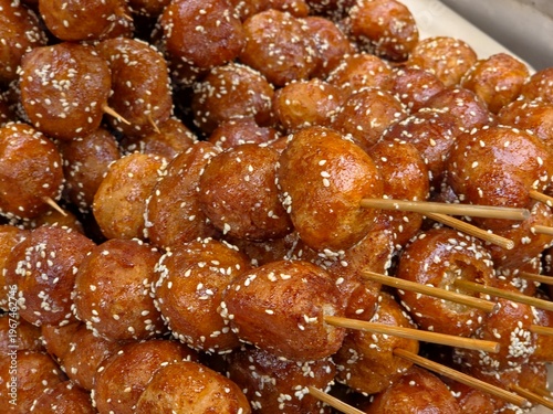 Obraz na plátně Tang You Guo Zi, a famous Chengdu street food, features deep-fried glutinous rice balls on skewers, coated in a shiny red sugar glaze and white sesame seeds