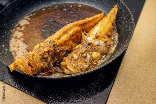 Very tasty fried sea fish on a frying pan, with a flour coating
