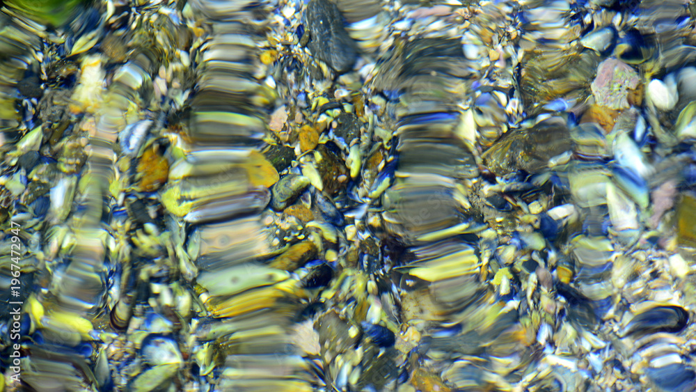 Fototapeta premium An artistic photograph capturing the distortion, reflection and refraction of light in moving water against a colourful background.