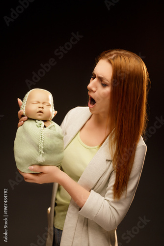 Woman with a surprised expression holding a baby training doll