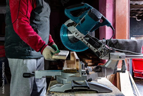 Carpenter using professional circular saw with a miter in the woodcraft carpentry workshop for cutting wooden board.