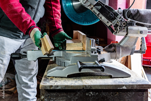 Carpenter using professional circular saw with a miter in the woodcraft carpentry workshop for cutting wooden board.