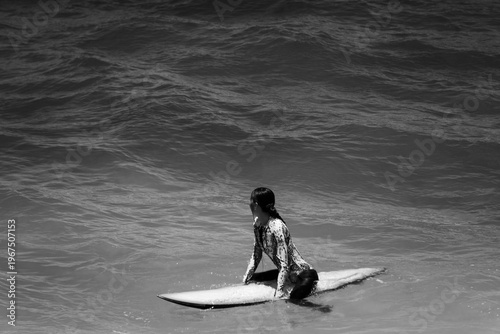 A beautiful girl surfs in a jumpsuit in the middle of the ocean waves