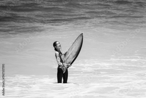 A beautiful girl surfs in a jumpsuit in the middle of the ocean waves