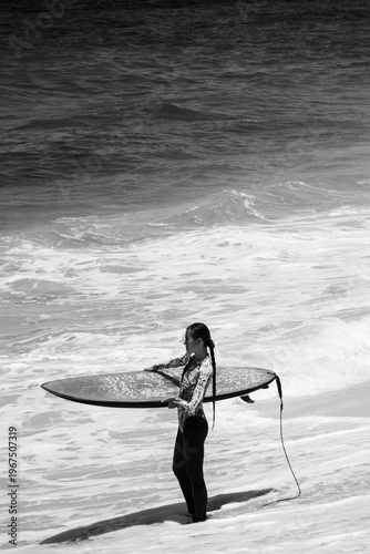A beautiful girl surfs in a jumpsuit in the middle of the ocean waves