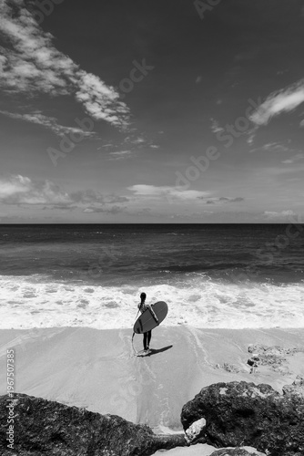 A beautiful girl surfs in a jumpsuit in the middle of the ocean waves