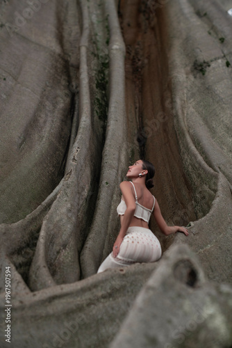 A beautiful girl in an elegant dress poses near an old tree