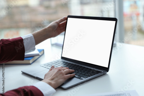 Businesswoman working with laptop at white table indoors, closeup