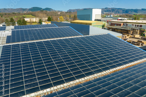 Quadro su tela Aerial view of solar power plant with blue photovoltaic panels mounted on industrial building roof for producing green ecological electricity