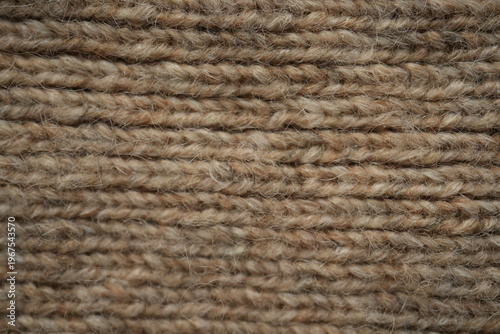 brown texture of knitted wool fabric as a background, white smooth symmetrical lines of hand-knitted needlework pattern	
