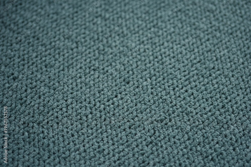 Fototapeta premium macro texture of soft green plush fabric. Close-up of cozy textile surface with delicate fibers and calm natural tones. Smooth and slightly fuzzy texture creates a relaxing background perfect for eco