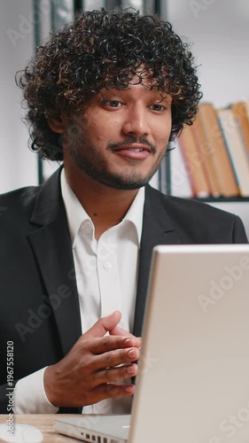 Indian businessman working on laptop computer at home office desk talk on online communication video call with employee, boss. Manager man freelancer support services looking at webcam of computer