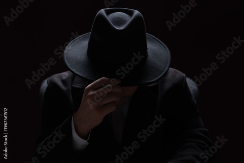 Bilde på lerret Man wearing stylish hat in armchair on black background