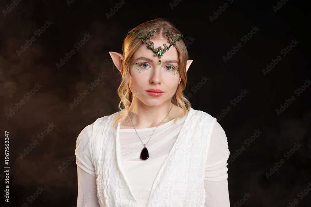 Obraz premium Beautiful girl dressed as elf on black background with smoke