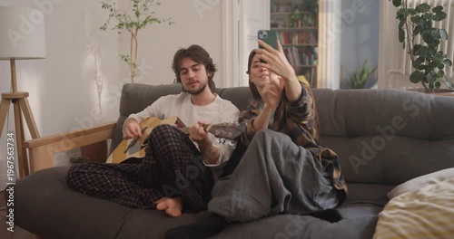 A couple strums a guitar and takes playful selfies on a relaxed afternoon at home