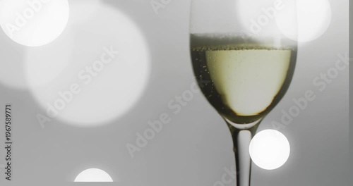 Bokeh discs appearing from left drifting across frame while flute holding bubbles, showing product