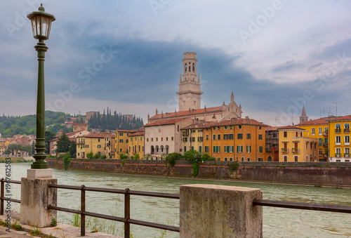 View of Verona across the Adige River with cathedral tower and historic riverside buildings, Italy.
