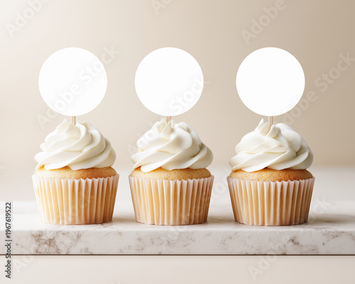 Vanilla cupcakes with cream frosting and blank round toppers