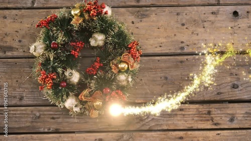 Animation of golden shooting star over christmas wreath icon on wooden surface with copy space