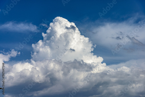 Cumulus white clouds bofies towering in clear blue sky background.