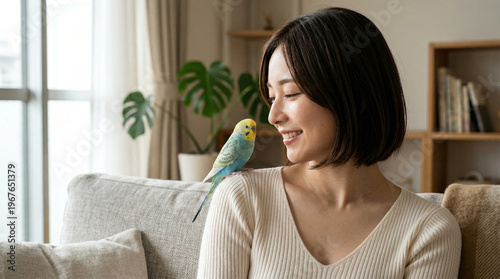 愛鳥のセキセイインコと心を通わせる穏やかな表情の女性 ライフスタイル