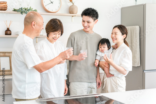 Photos A three-generation family drinking water in their home kitchen.