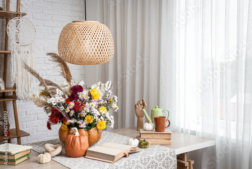 Books and pumpkin with autumn bouquet on table in interior of living room