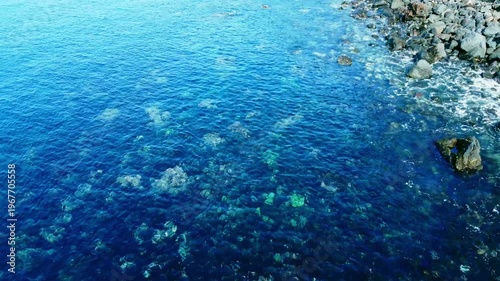 海底が見える穏やかな波打ち際を俯瞰で空撮