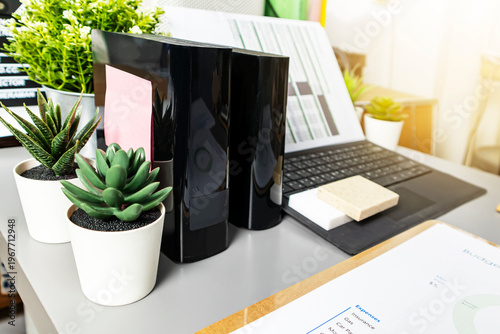 The desk of an administrative staff member, with a laptop and company documents on it.
