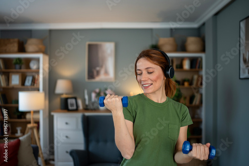Photos Woman exercising with dumbbells at home listening music