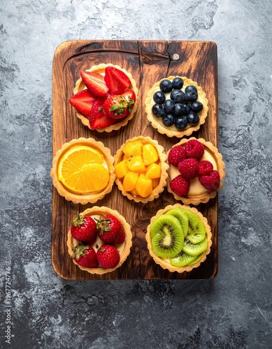Assortment of Colorful Fruit Tarts on a Wooden Board.